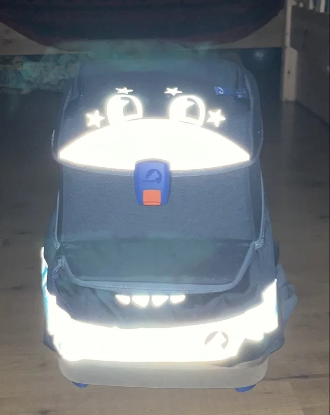 Schulranzen mit Augen, Zähnen und Zunge als Reflektoren mit Blitzlicht fotografiert.