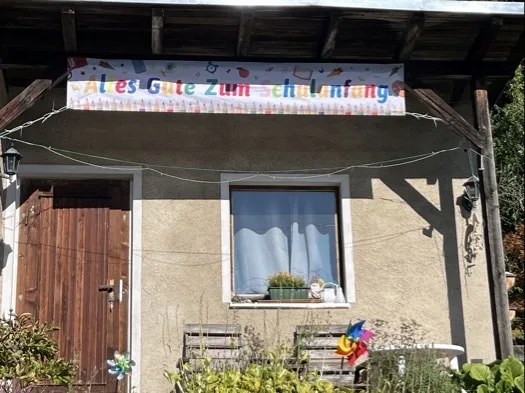 Am Gartenhaus gespanntes Transparent „Alles Gute zum Schulanfang“ befestigt mit mehr als zehn Kabelbindern