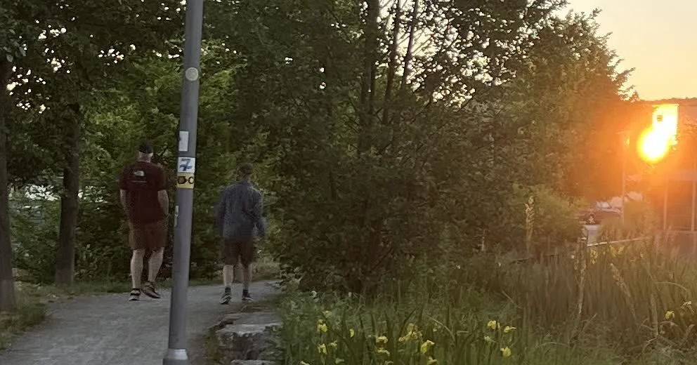 Wanderer im Hintergrund; Reflexion der Sonne in einem Fenster vorne rechts