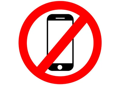 Ein schwarzes Smartphone ist von einem roten Verbotszeichen – einem Kreis mit diagonalem Balken – überlagert. Das Symbol steht für „Handys verboten“.