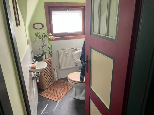 Aufnahme eines Toilettenraumes von außen durch die Tür, Blickrichtung zum Fenster