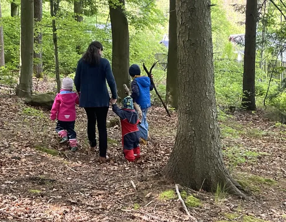 Frau mit drei Kindern im Wald, von hinten fotografiert