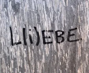 Wort in einen Holzbalken geritzt: L(i)ebe 