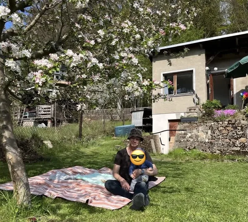 Der Autor mit seinem jüngsten Kind vor dem Gartenhaus unter einem blühenden Apfelbaum