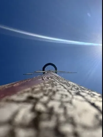 von unten fotografierter in den blauen Himmel ragender Mast