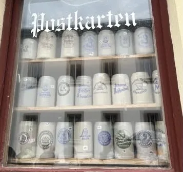 Fenster mit Bierkügen. Am Fenster oben die Aufschrift: Postkarten
